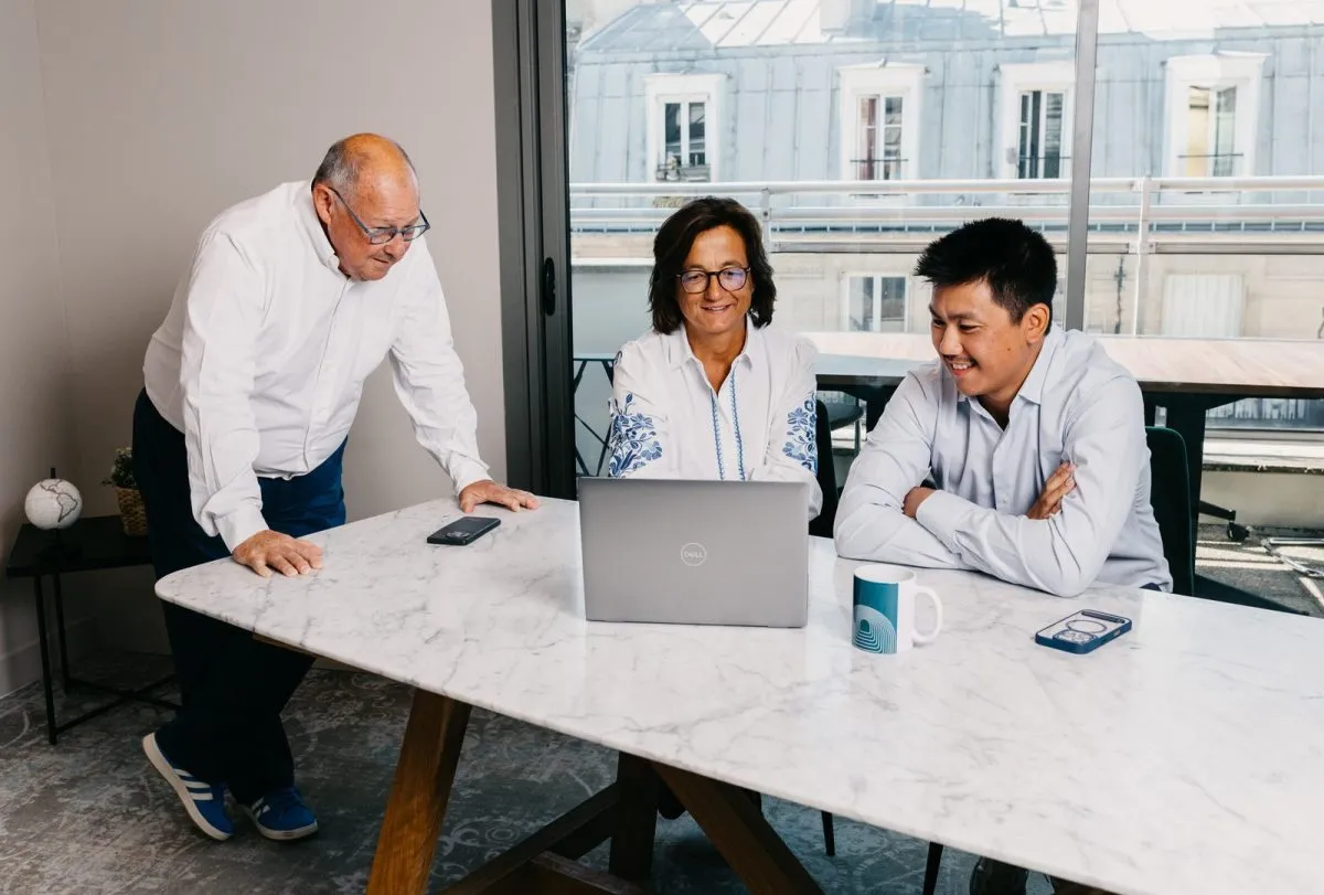 Three consultants gathered around a laptop during a working session