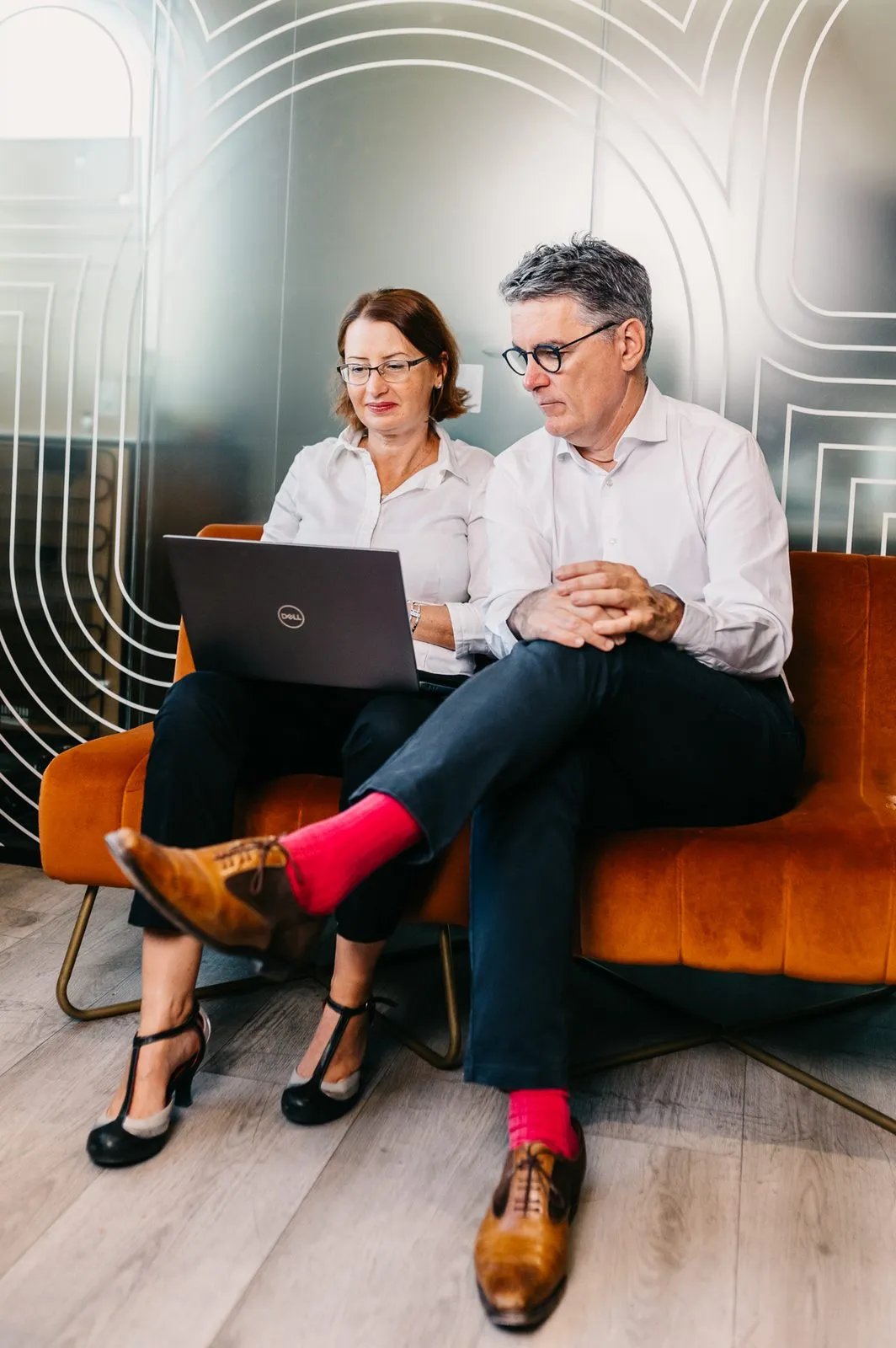 Two consultants discussing around a laptop on a sofa