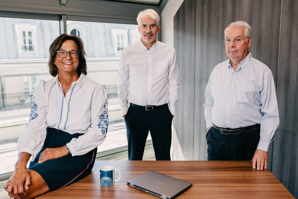 Three team members standing in front of the bay windows