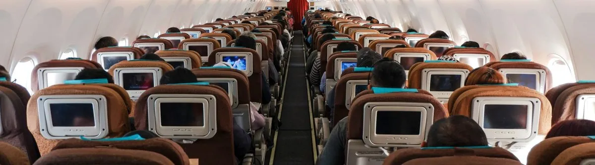 Airliner cabin full of passengers, rows of seats on either side of the aisle